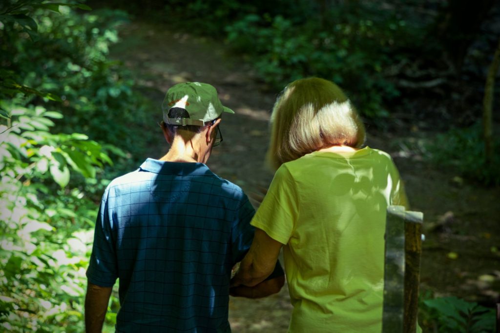 Older couple walking through a shaded forest path