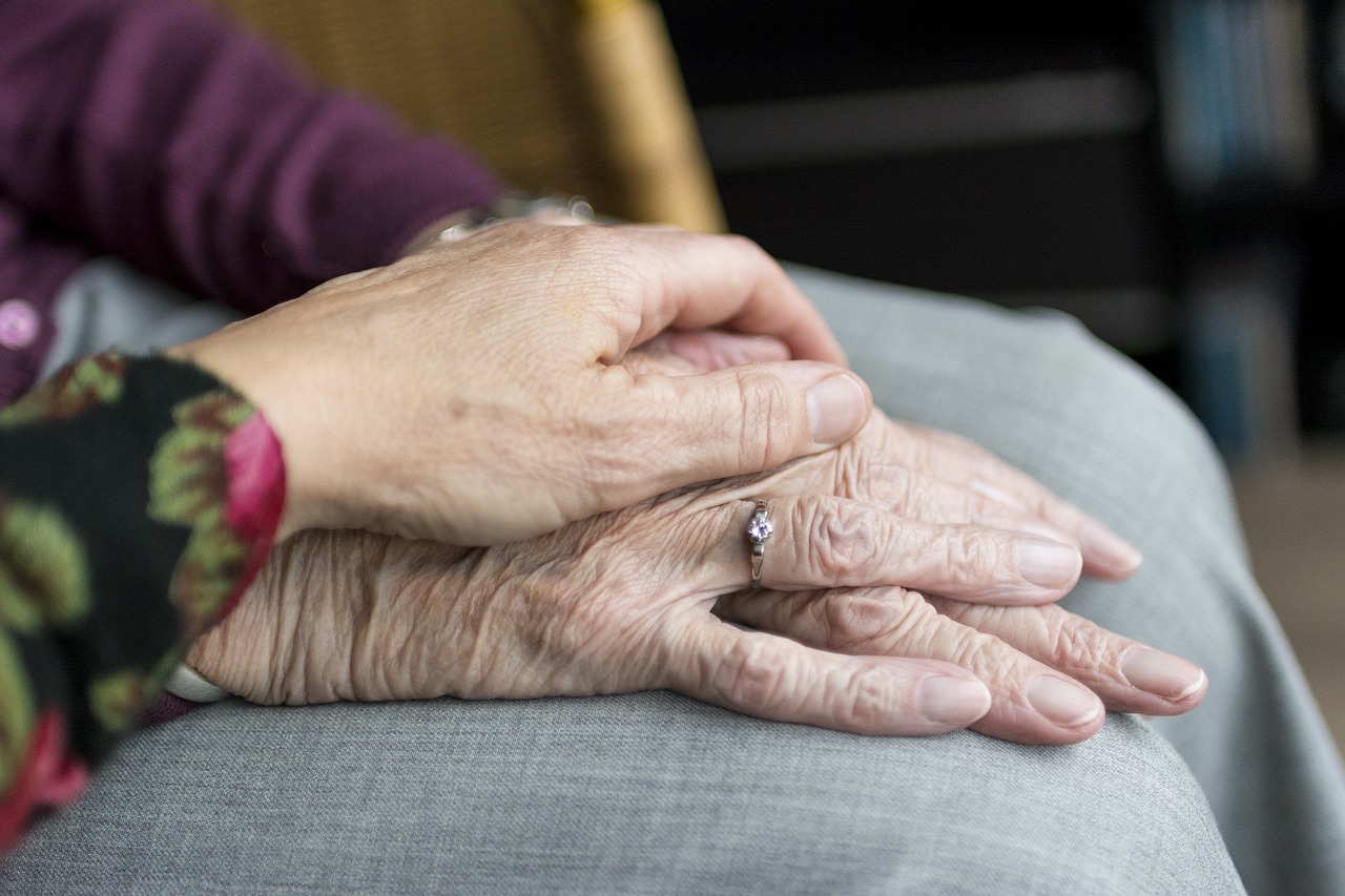 Two elderly hands, one resting over another