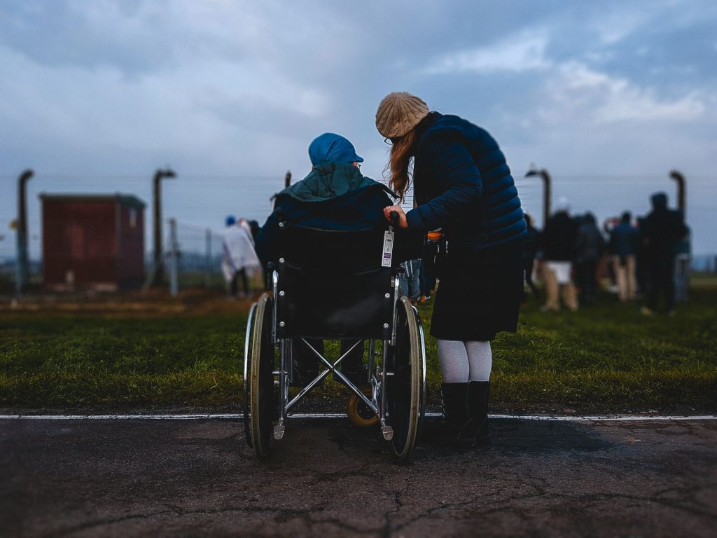 Caregiver standing with person in a wheelchair outdoors