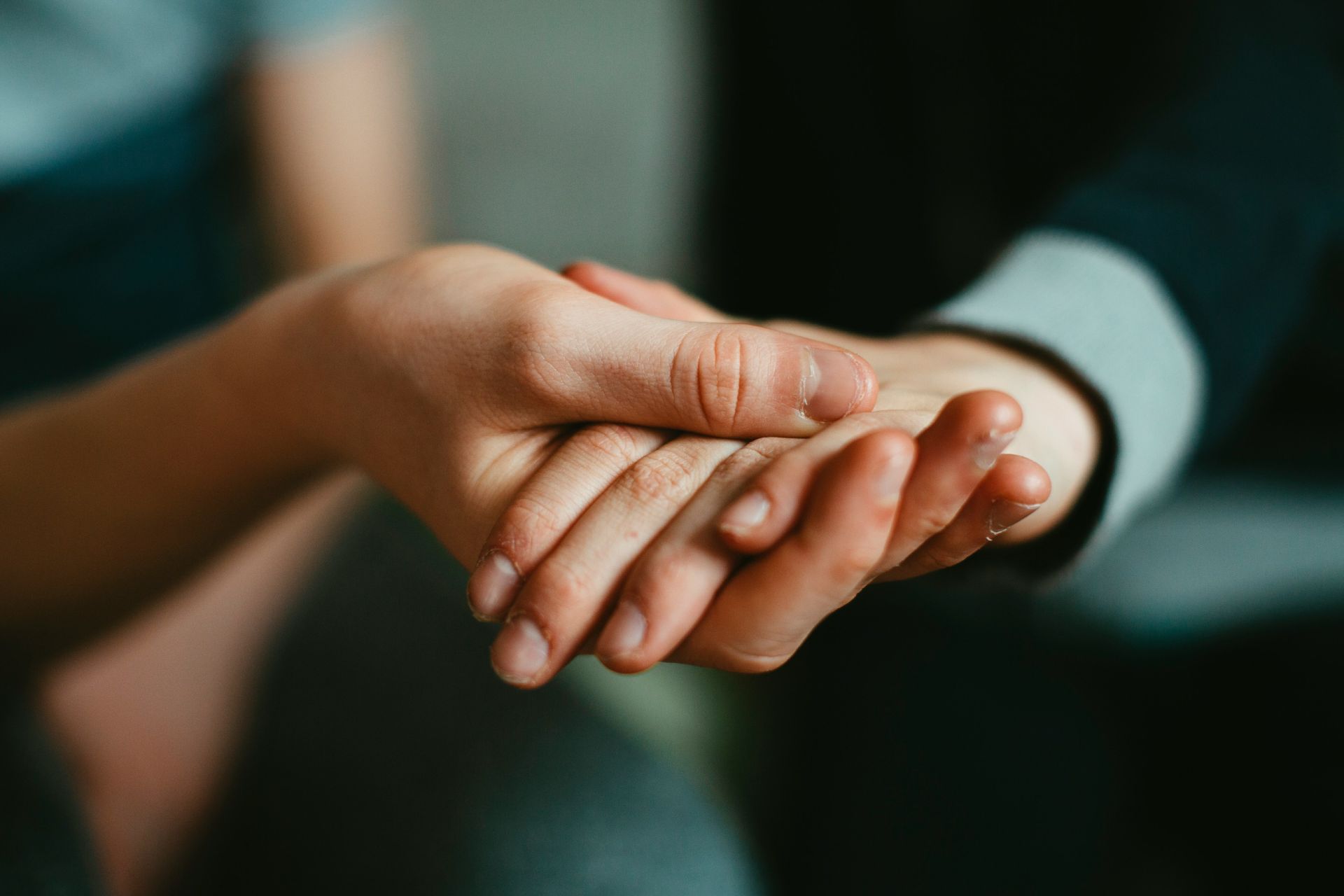 One person gently holding another's hand