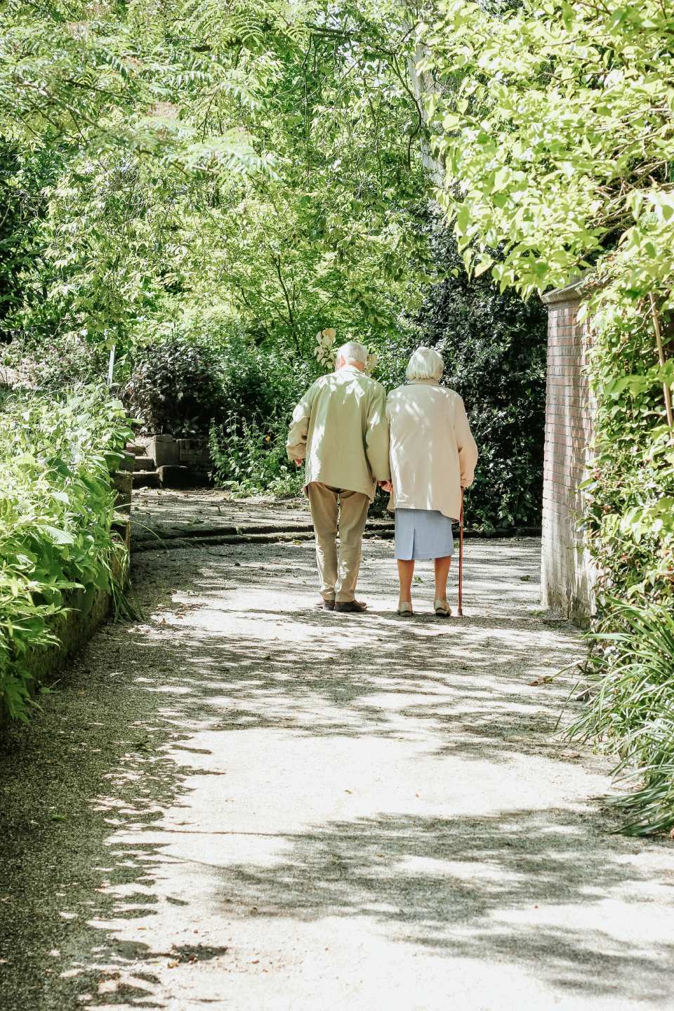 Elderly couple walking on a shaded pathway