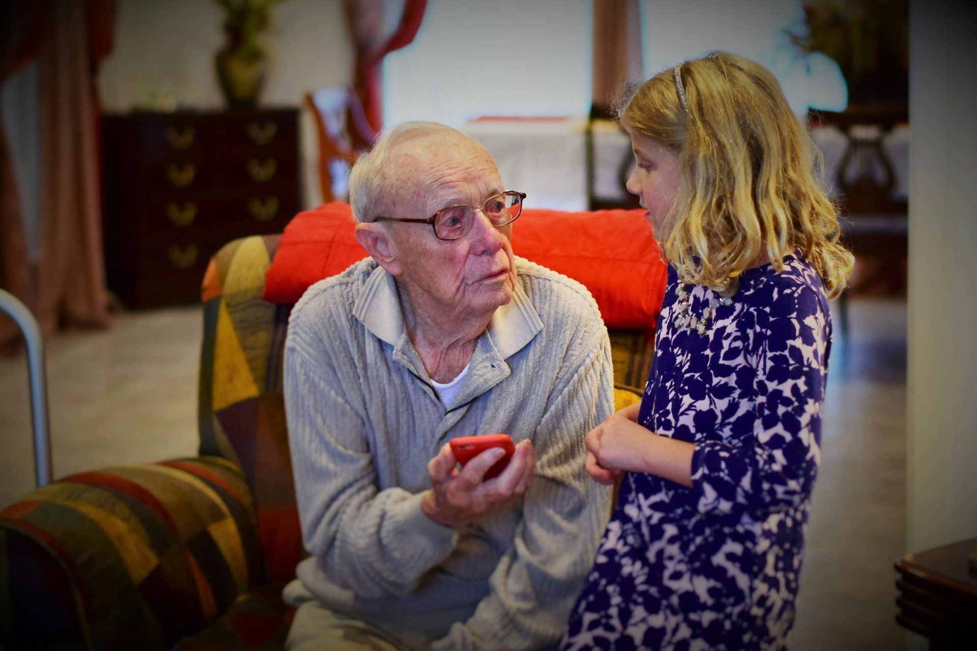 Grandfather talking to young girl, indoors